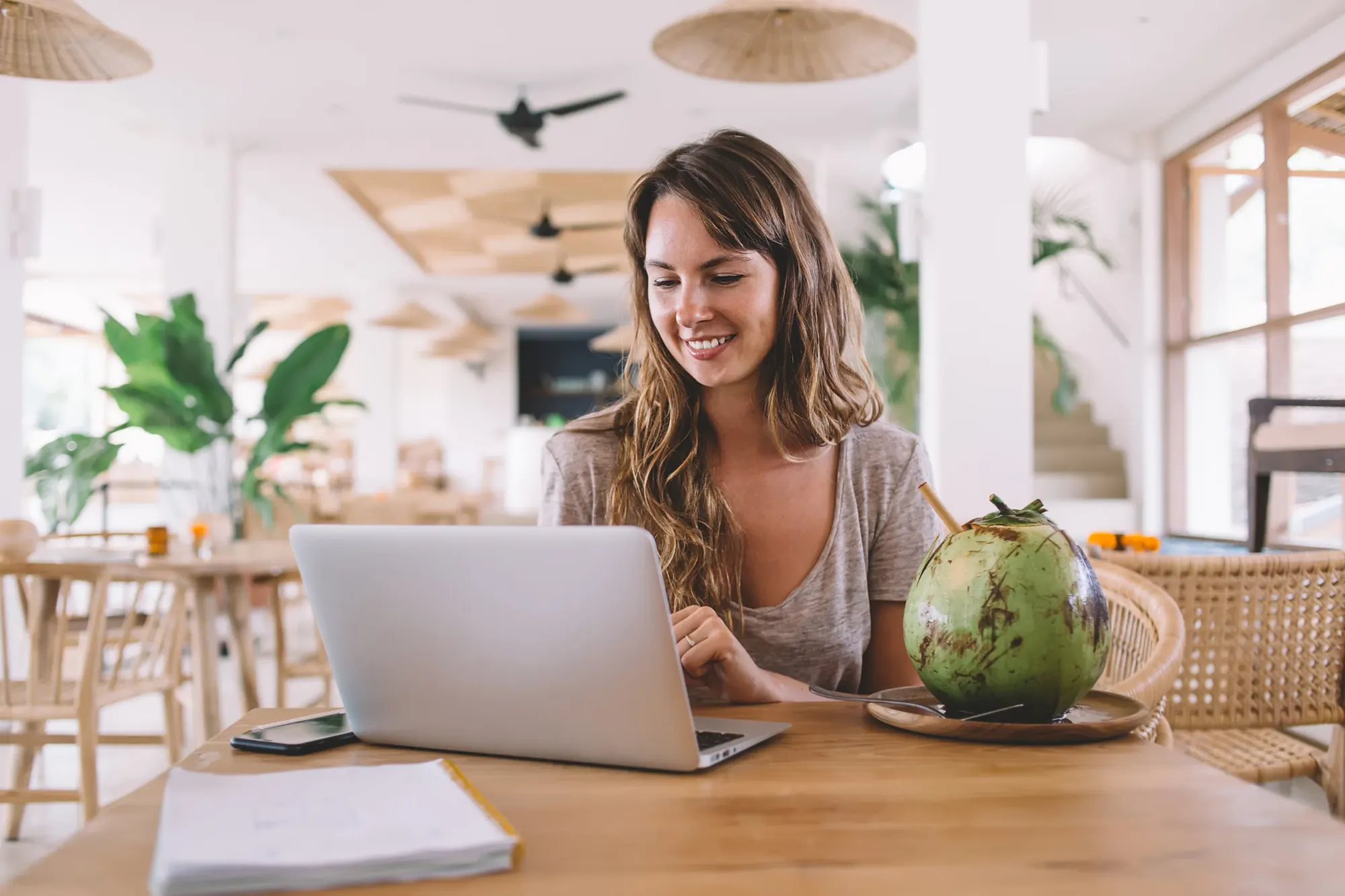 Student working on a laptop in a bright Bali cafe