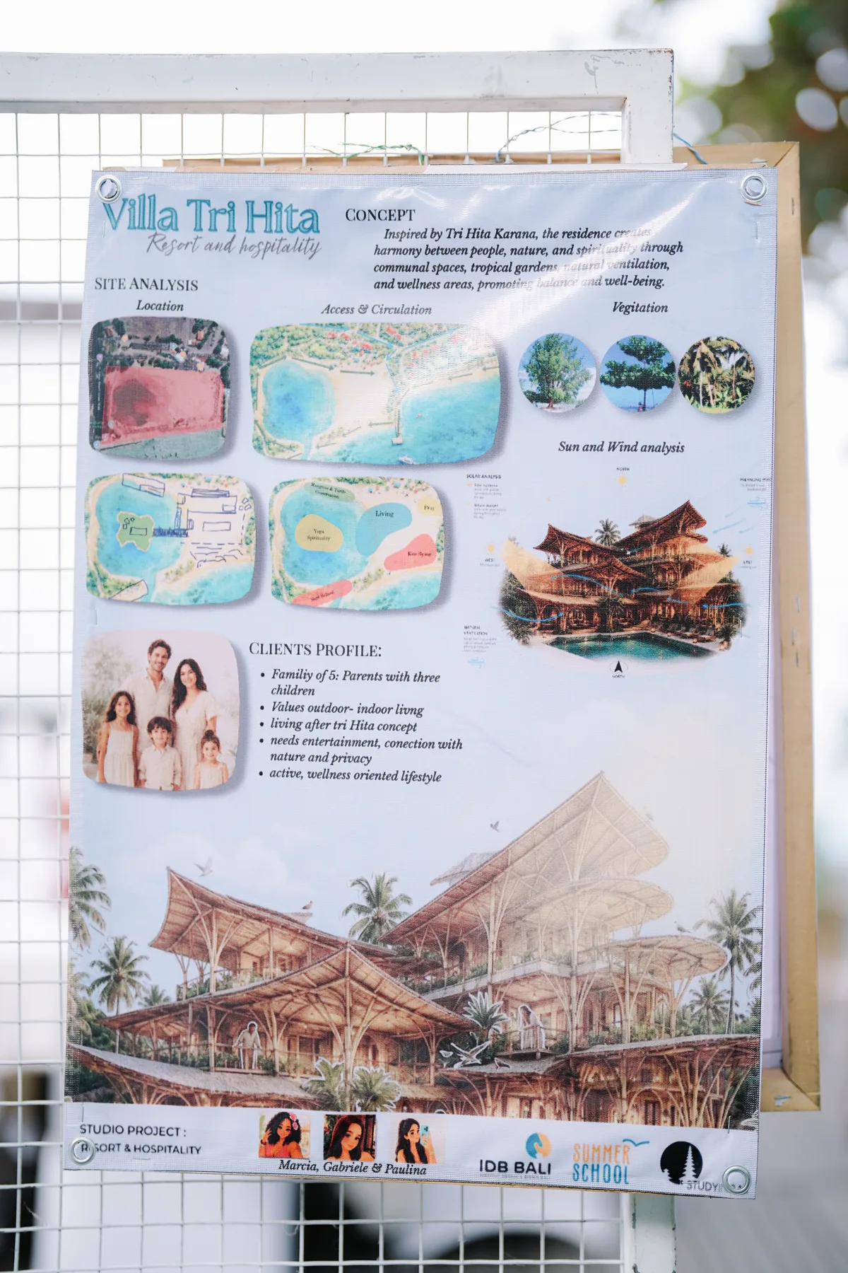 A studio project poster titled Villa Tri Hita pinned to a fence, showing site plans and a rendered resort building