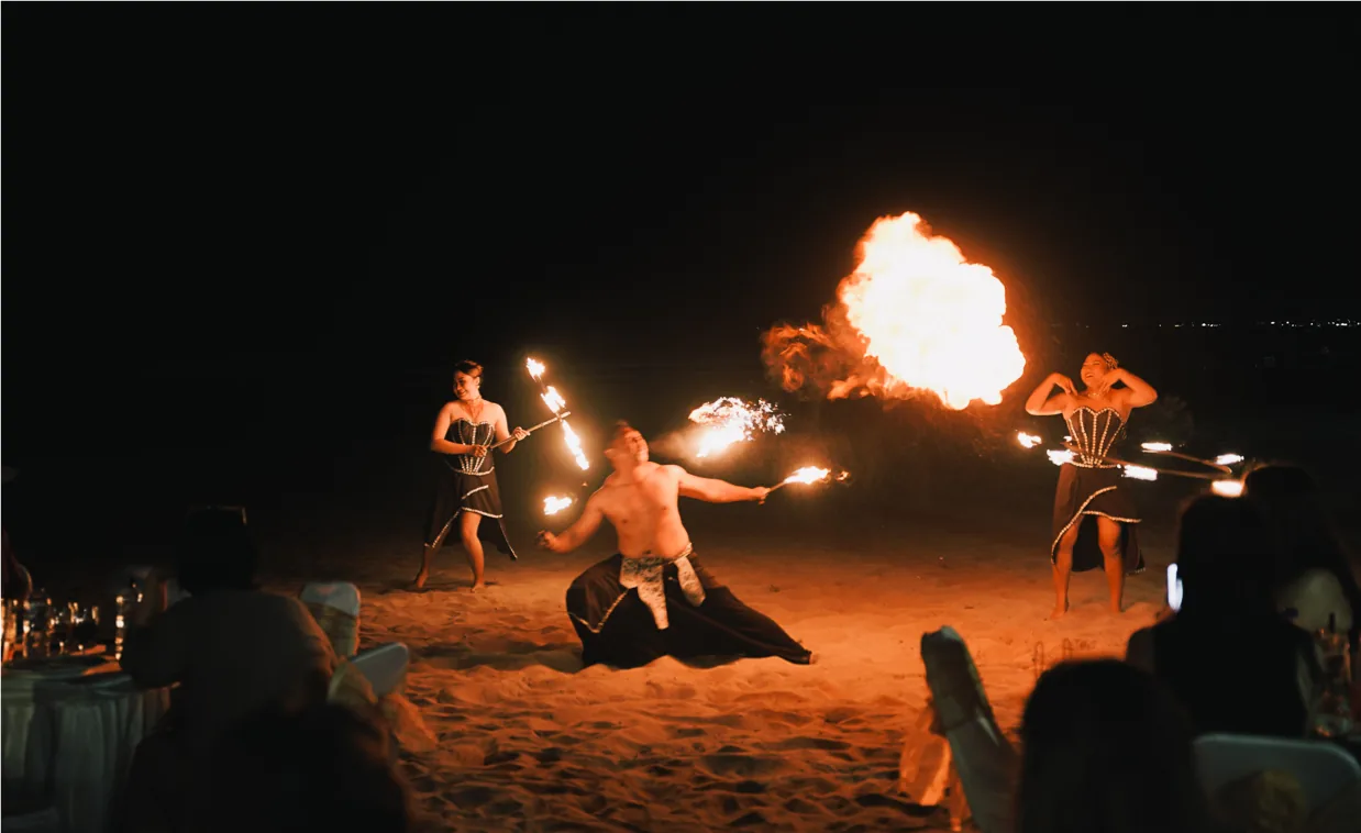 Fire dancers performing on the beach in front of the group