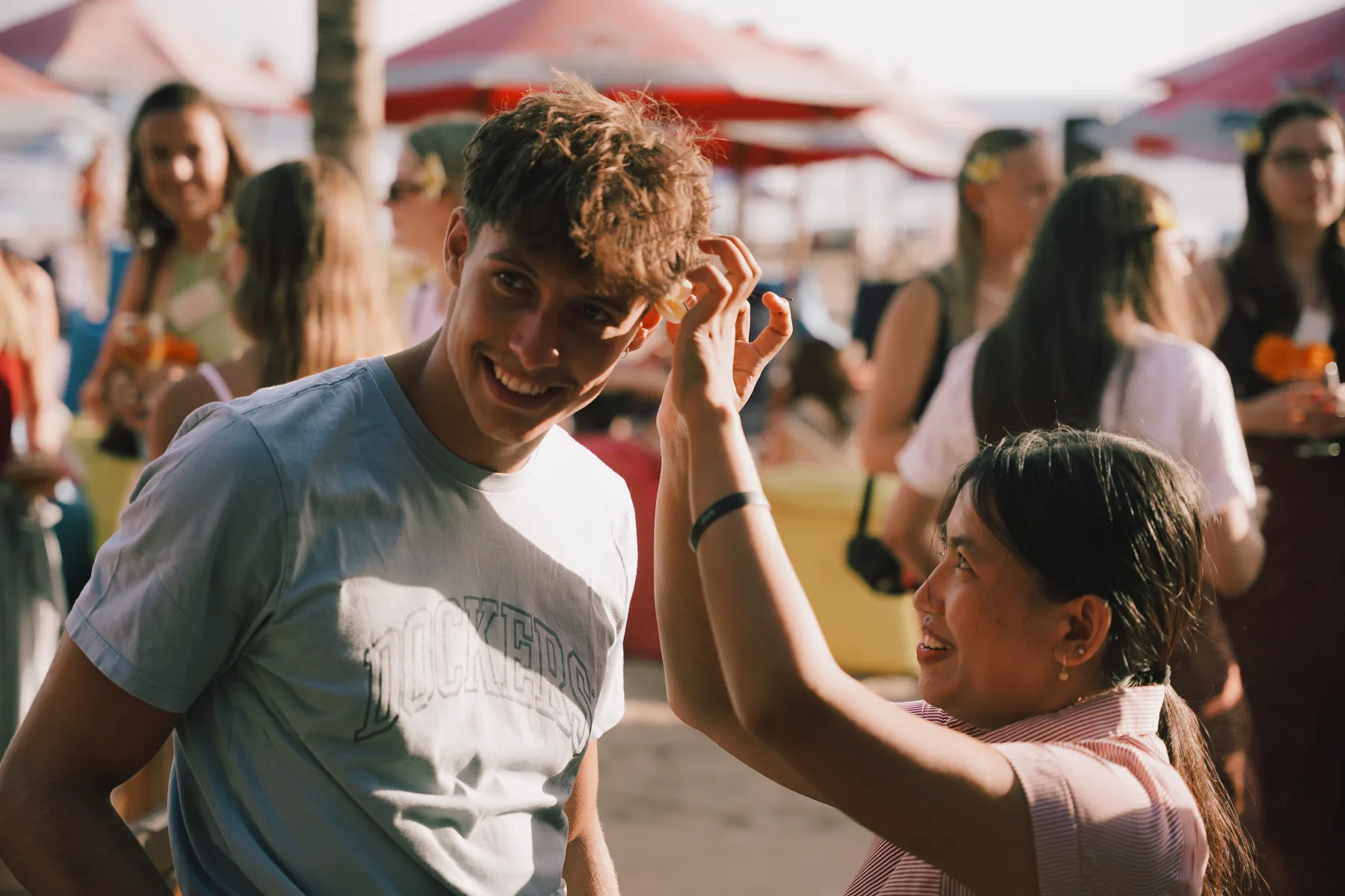 A staff member adjusting a student's hair while he laughs