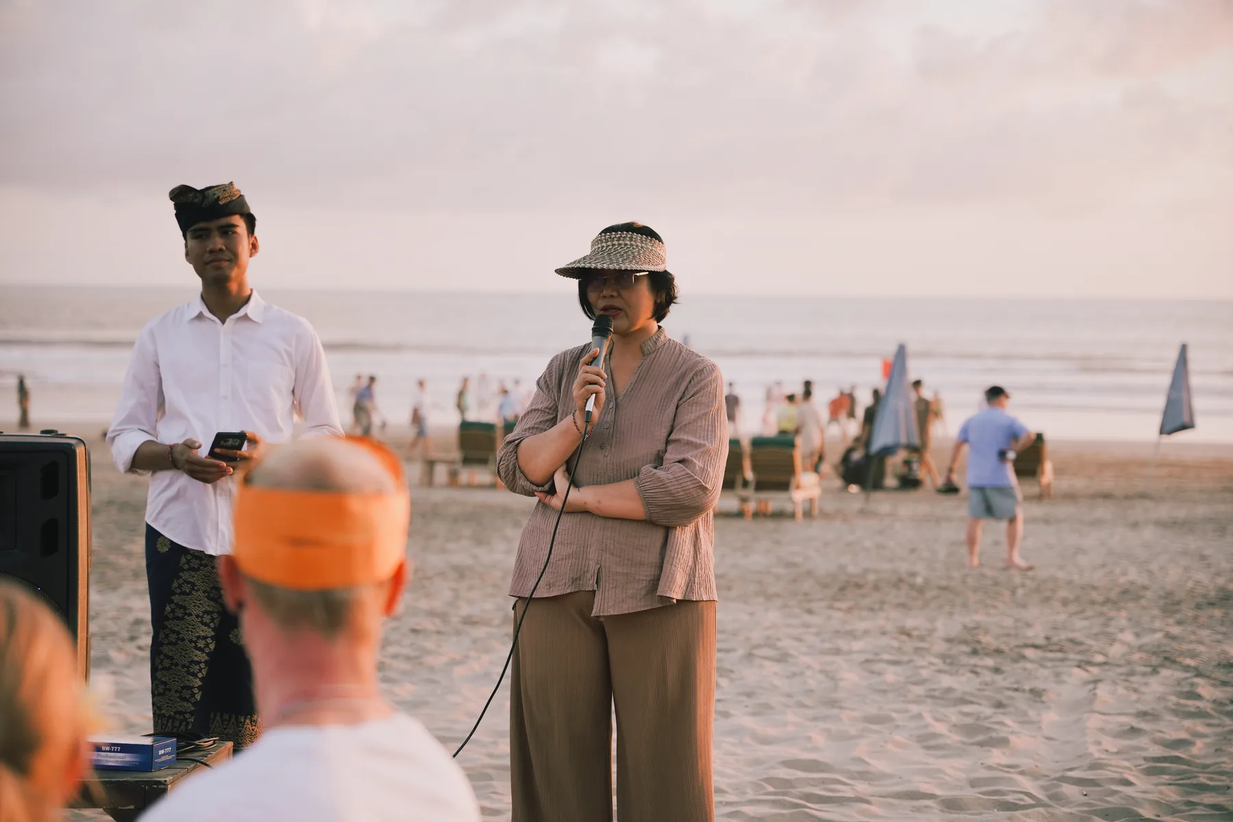 A staff member and a guest speaker addressing the group with a microphone on the beach