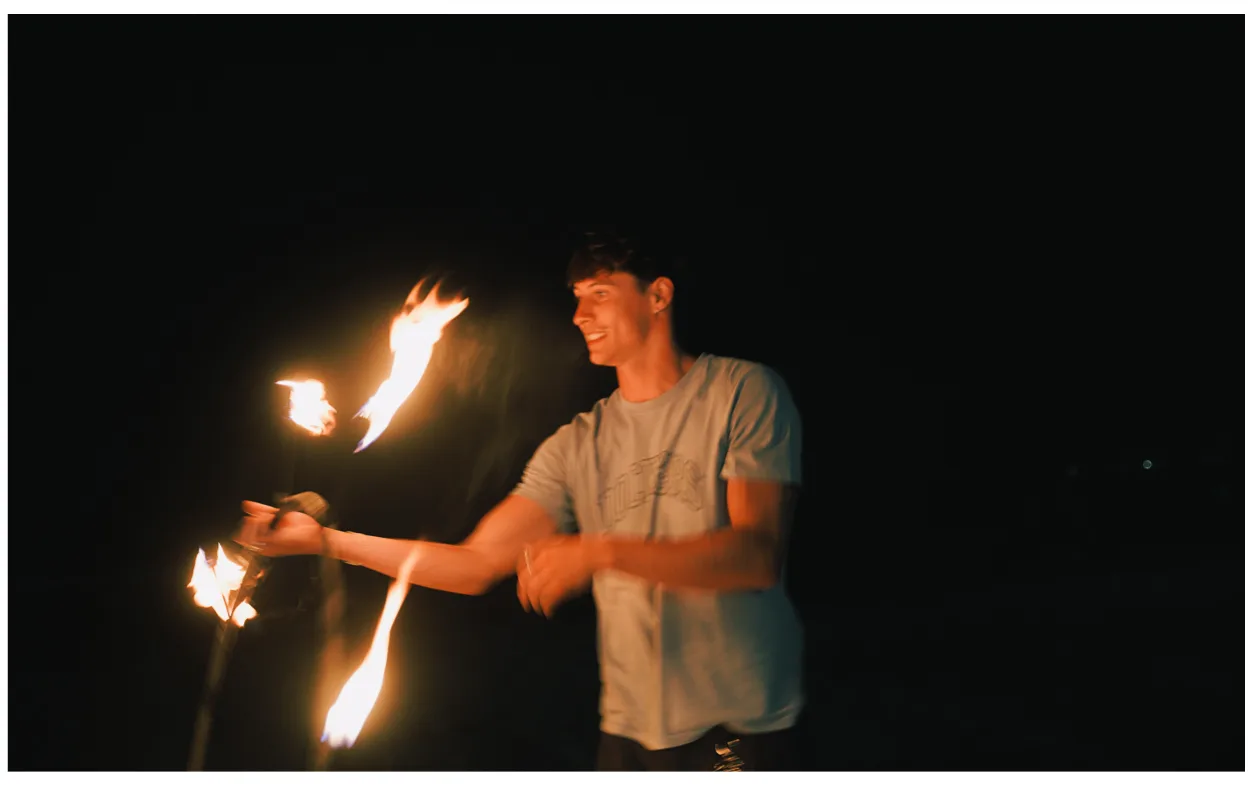 A student holding two lit torches during the fire show