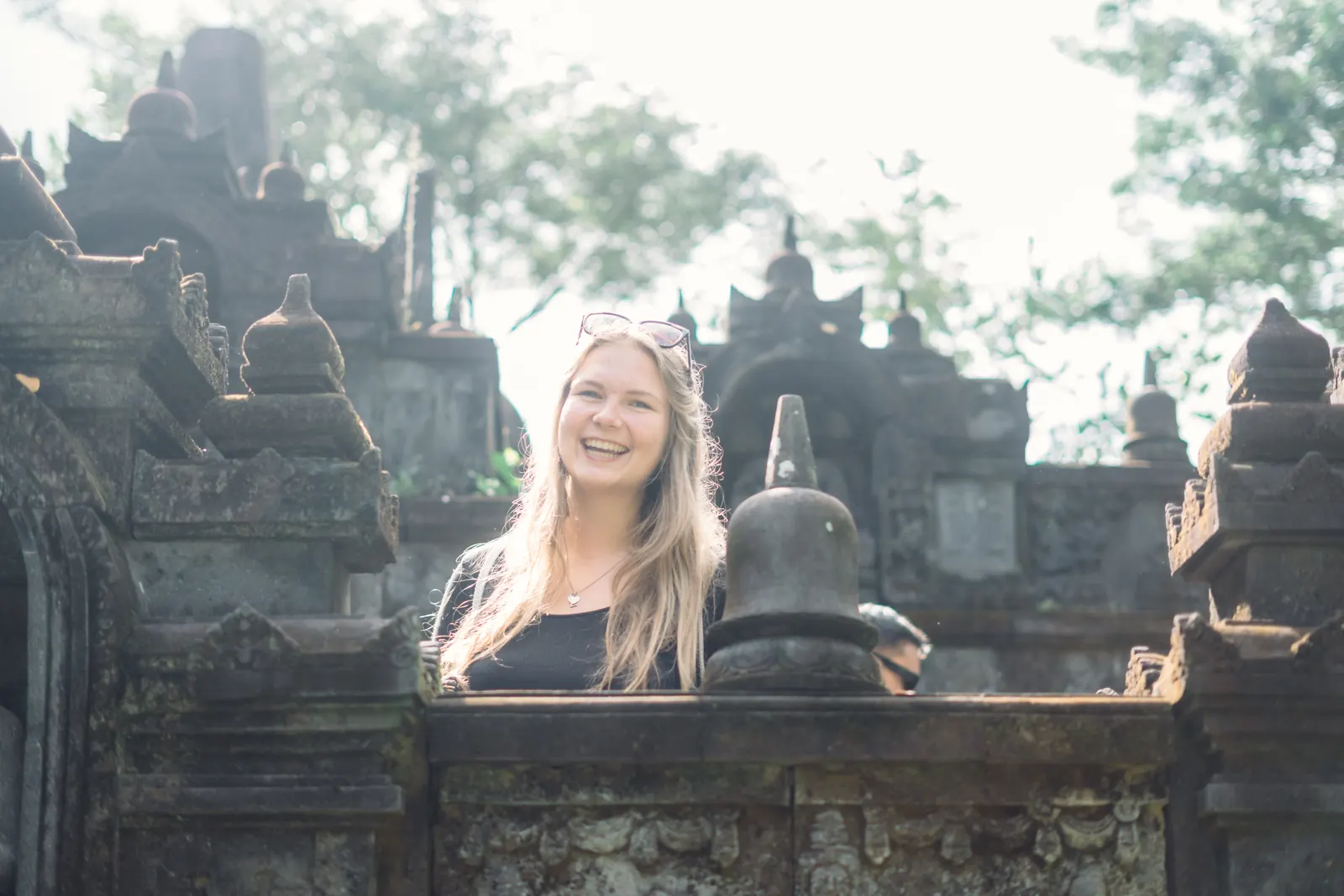 A student laughing among the stone shrines of a Balinese temple